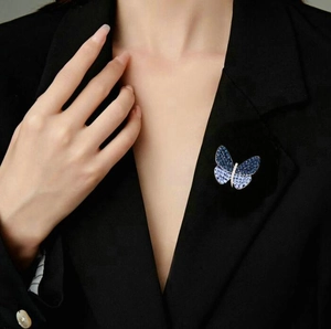 Close-up of a blue crystal butterfly brooch pinned on a black suit jacket lapel