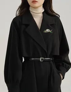 Macro detail of a panda brooch on a bamboo branch pinned to a black wool coat lapel