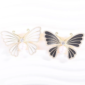Broches papillon élégantes avec perles et cristaux sur fond de soie blanche soyeuse