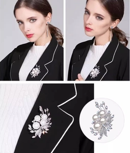 Detail of silver pearl brooch with rhinestones on black blazer for elegant styling