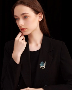 Detail of a gold leaf brooch with blue crystals on a black blazer lapel for luxury styling