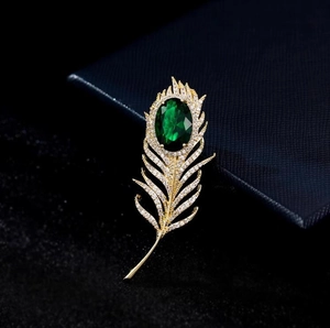 Broche luxueuse en plumes dorées avec pierre émeraude verte et détails en zircone