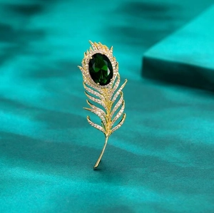 Détail de la broche plume dorée de luxe avec gemme verte et zircons étincelants