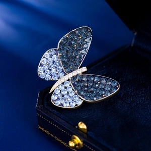 Elegant gold butterfly brooch with blue gradient crystals on a dark blue velvet box