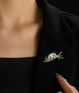 Detailed close-up of a panda brooch with green bamboo leaves on a black suit lapel