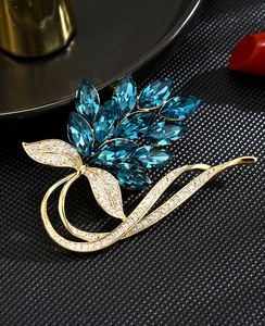 Close-up of elegant gold brooch with dark blue marquise crystals and pavé diamonds