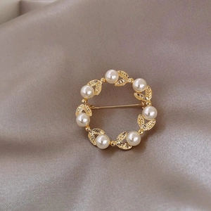Vue détaillée de la broche ronde en feuilles d'or avec perles blanches élégantes