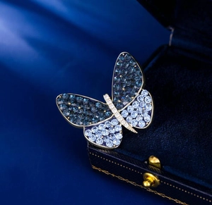 Close-up of butterfly brooch with blue rhinestones on a navy velvet jewelry box