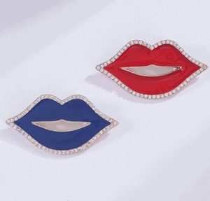 Dettaglio di spille a labbra rosse e blu con bordi in strass scintillanti e smalto lucido