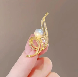 Vue détaillée d'une broche fleur dorée avec une grande perle et des oxydes de zirconium