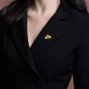 Close-up of a luxury bee brooch with gold and black stripes on a black blazer