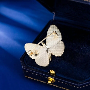 Close-up of the golden butterfly brooch back with a secure rotating pin and matte metal texture
