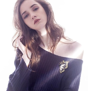 Elegant butterfly cat-eye stone brooch pinned on a dark off-shoulder knitted sweater