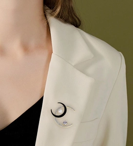 Elegant gold and black crescent moon brooch with pearls and zircons on a blazer lapel