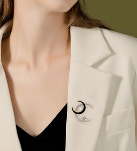 Detail view of double moon brooch with zircon and pearl on a beige suit blazer