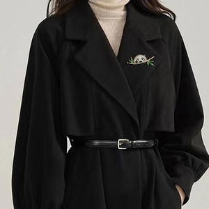 Cute panda brooch with green bamboo leaves pinned on a black wool coat lapel