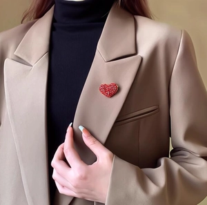 Elegante spilla a cuore rosso con strass appuntata sul risvolto di una giacca kaki