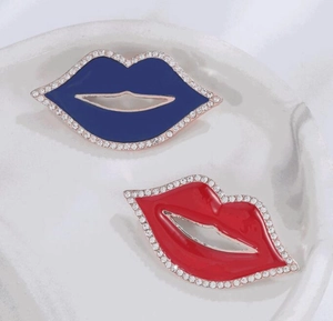 Dettaglio di mini spille a forma di labbra in smalto rosso e blu con strass lucidi