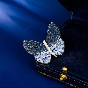 Elegant butterfly brooch in gold metal with blue gradient crystals on a velvet box