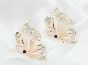 Detailed close-up of butterfly brooch with opal wings and rhinestones on white silk