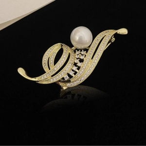 Élégante broche fleur dorée avec une grande perle blanche et des zircons sur fond noir