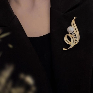 Élégante broche fleur dorée avec perle et zircons brillants sur tissu noir