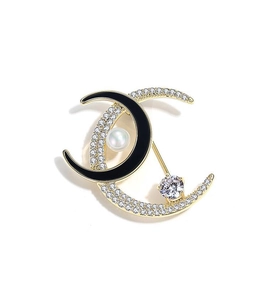 Detail of moon-shaped brooch with inlaid rhinestones and elegant white pearl accents