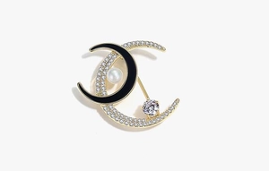 Detailed view of crescent moon brooch with black enamel, zircon stones and white pearl
