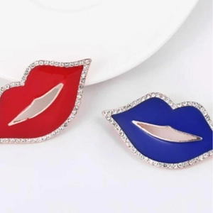 Mini spille a forma di labbra rosse e blu con strass e smalto su sfondo bianco