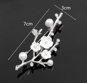 Broche fleur de prunier élégante avec perles blanches et cristaux sur fond noir poli
