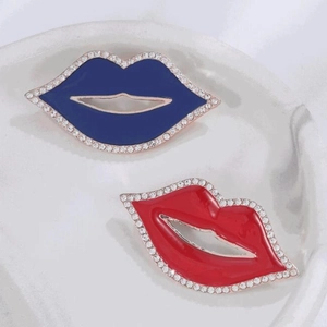 Mini spille a forma di labbra rosse e blu con strass su vassoio di ceramica bianca