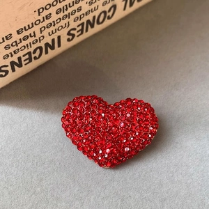 Vista dettagliata della spilla a cuore rosso di lusso con strass su base dorata