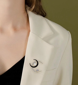 Detail of elegant crescent moon brooch with black enamel, crystals and pearl on suit jacket