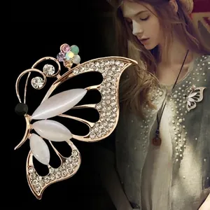 Elegant gold butterfly brooch with cat eye stone and colorful rhinestones on a blazer
