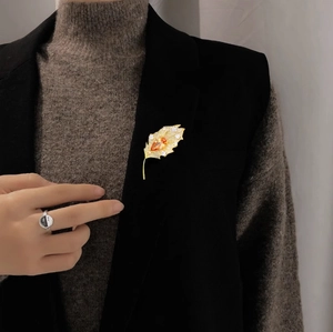 Detail of elegant gold leaf brooch with orange gemstone pinned on a black suit blazer