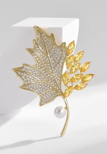 Macro detail of maple leaf brooch featuring yellow crystals, pavé zircon, and a white pearl