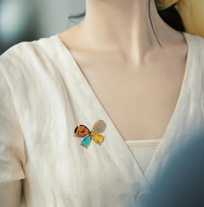 Edle Schmetterlingsbrosche in Gold mit farbigen Edelsteinen auf einer Baumwollbluse
