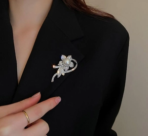 Close-up of a silver flower brooch with pearl and rhinestones on a black suit lapel