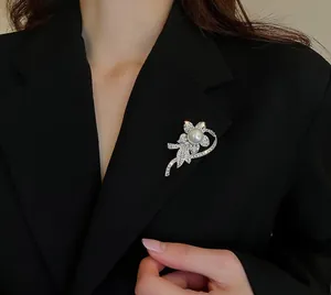 Close-up of a silver flower brooch with rhinestones and a pearl on a black blazer
