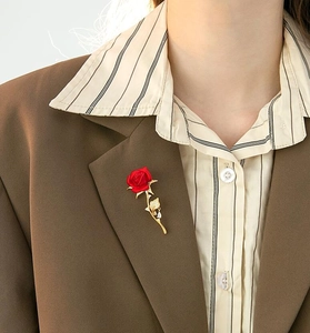 Elegant red rose brooch with gold leaves and crystals pinned on a professional suit