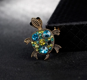 Macro shot of luxury crystal sea turtle brooch featuring colorful gemstones and gold finish