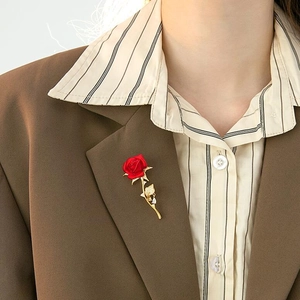 Detail of red rose brooch with gold leaves and crystal droplet on a blazer lapel