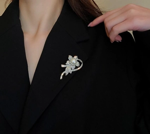 Detail of a floral brooch with white pearl and sparkling crystals on a black blazer lapel