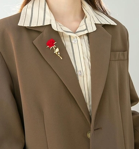 Close-up of a velvet red rose brooch with golden leaves pinned on a suit lapel