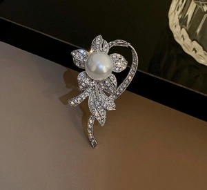 Detailed macro view of silver flower brooch featuring a large pearl center and rhinestones