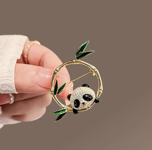 Dettaglio di una spilla a panda con foglie di bambù verdi e pietre di zircone bianco