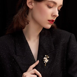 Elegant jasmine flower brooch with pearls on golden stems pinned to a black tweed jacket