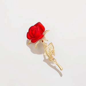 Detailed view of red rose brooch with gold-tone metal base and sparkling crystal accents
