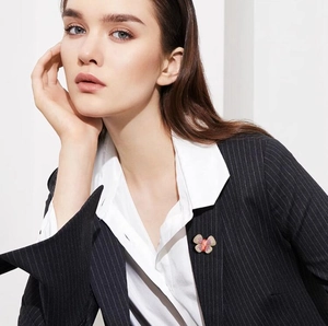 Elegant butterfly brooch with gold and purple accents pinned to a black striped suit lapel