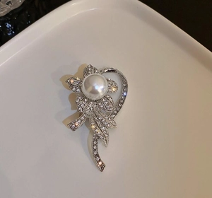 Close-up of silver floral brooch with radiant rhinestones and large white pearl center